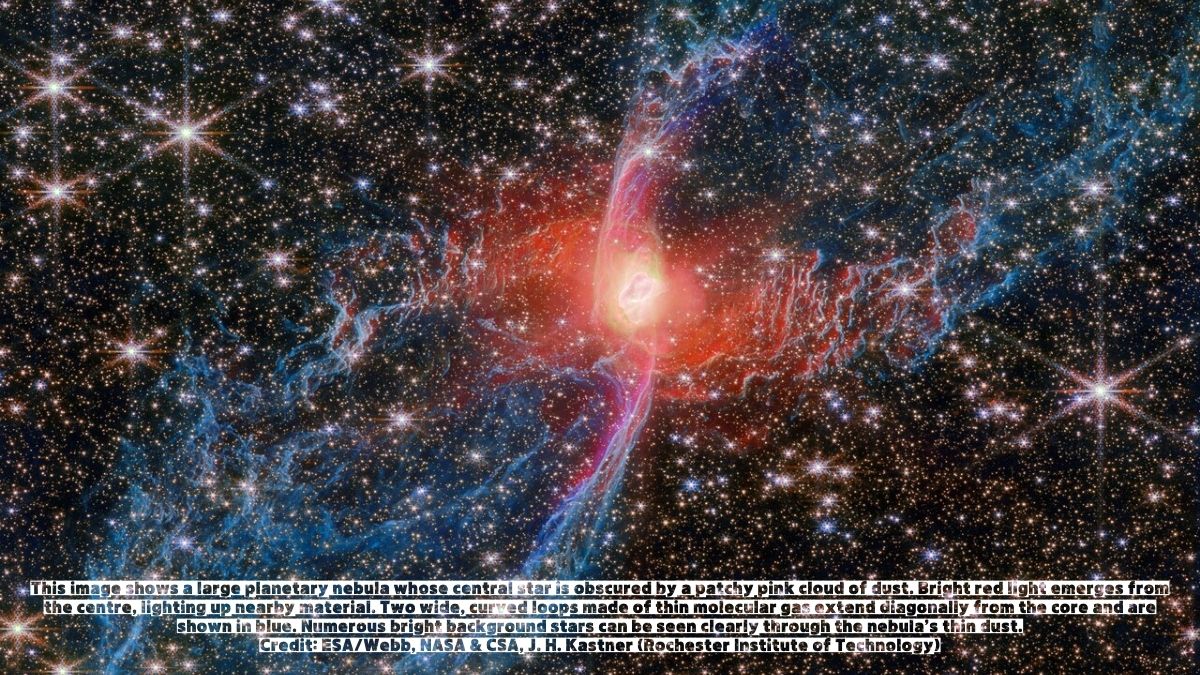 This image shows a large planetary nebula whose central star is obscured by a patchy pink cloud of dust. Bright red light emerges from the centre, lighting up nearby material. Two wide, curved loops made of thin molecular gas extend diagonally from the core and are shown in blue. Numerous bright background stars can be seen clearly through the nebula’s thin dust.